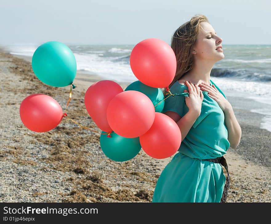 Emotional girl with balloons on the sea shore