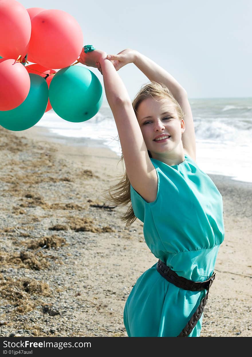 Emotional girl with balloons on the sea shore