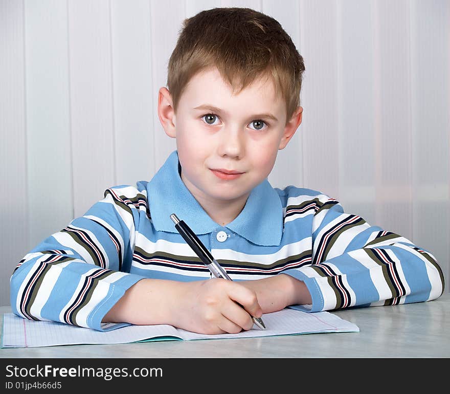 The litle boy doing homework on the table. The litle boy doing homework on the table