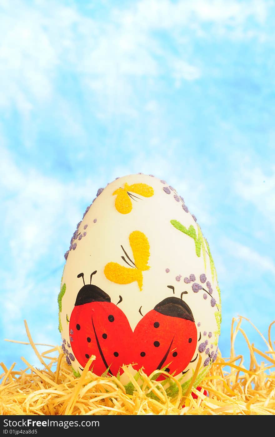 Easter egg in yellow straw on blue background