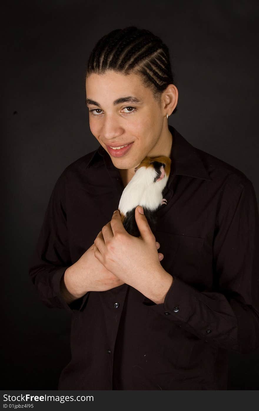 Aruban sexy male is holding a guinea pig on black