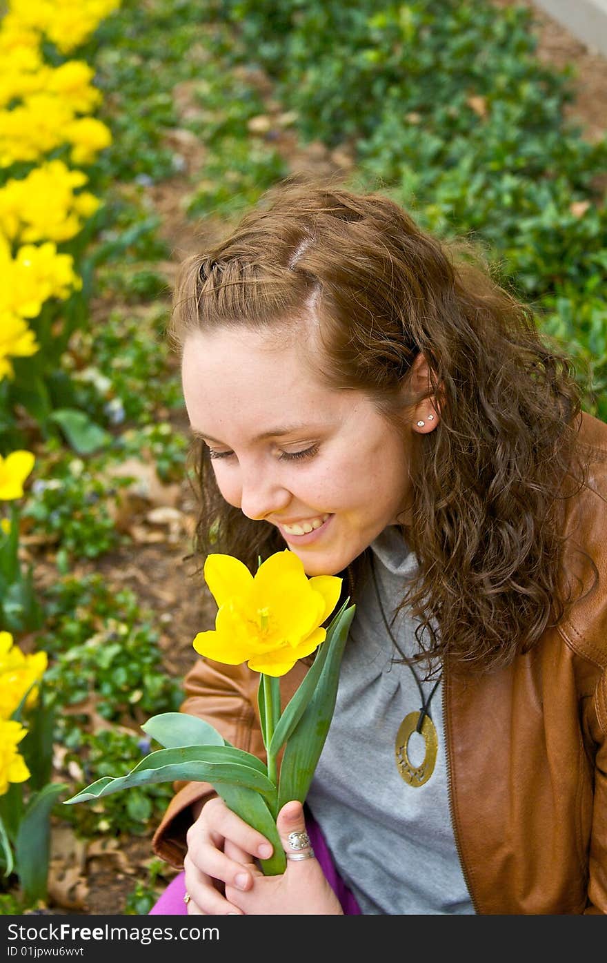 A pretty young girl smells an early spring flower. A pretty young girl smells an early spring flower