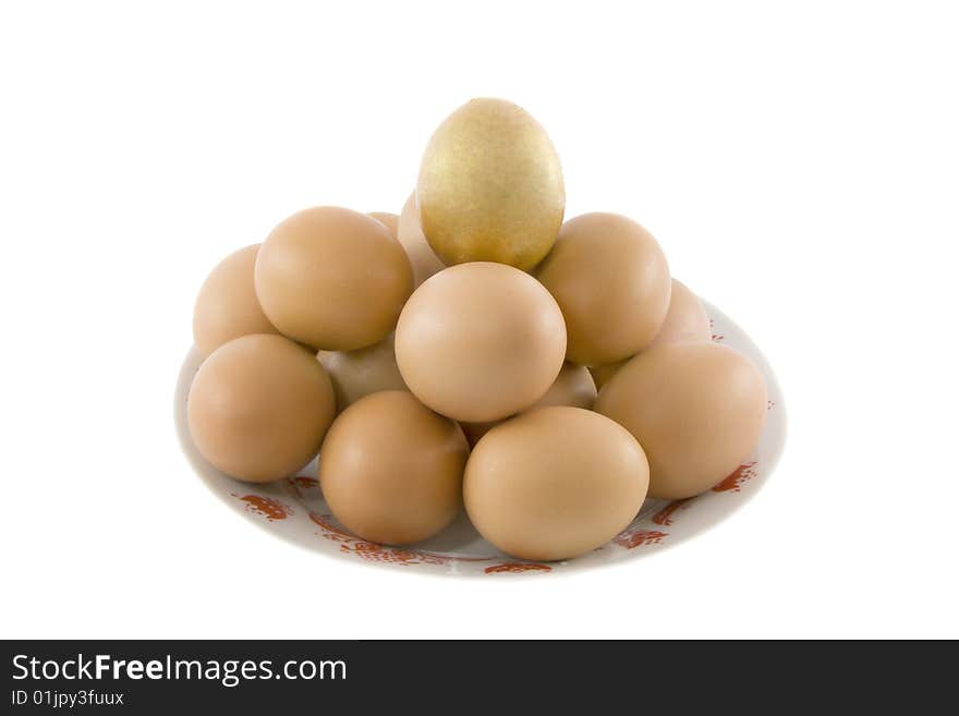 One golden and many ordinary easter rural eggs lying in white porcelain plate with a red ornament. One golden and many ordinary easter rural eggs lying in white porcelain plate with a red ornament