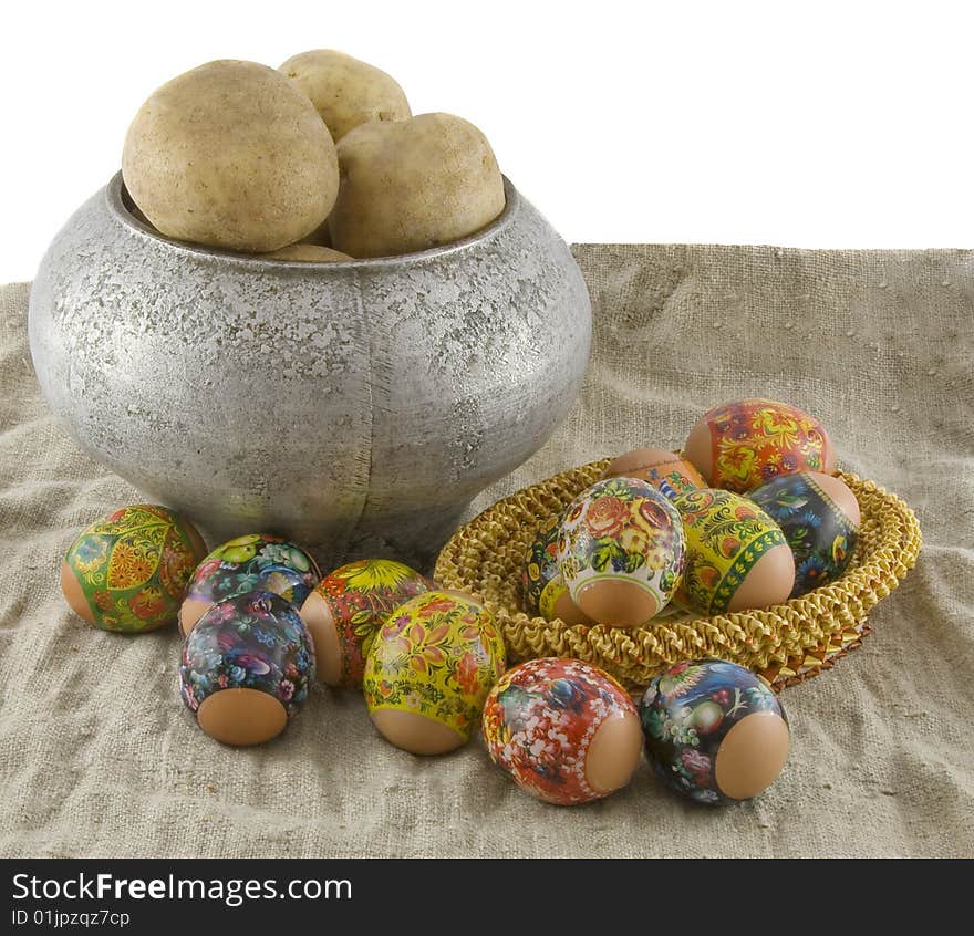 Still-life from vegetarian food. Fresh eggs lying in a wattled small basket,  boiled potato in a pig-iron kettle