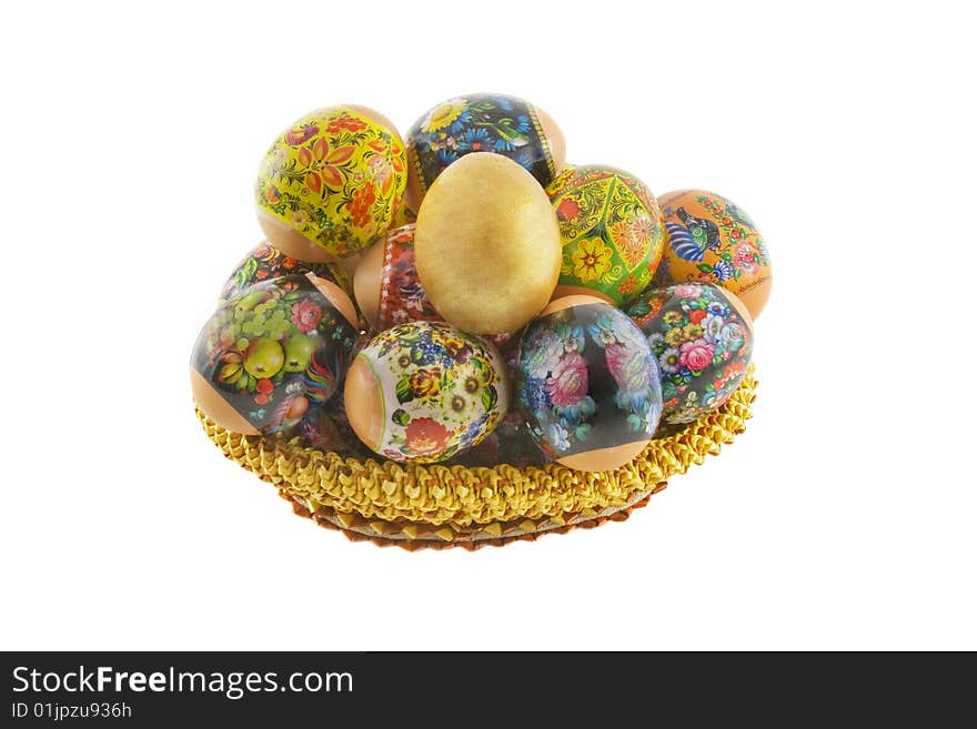 Many easter decorated eggs lying in a basket weaved from straw isolated over white background