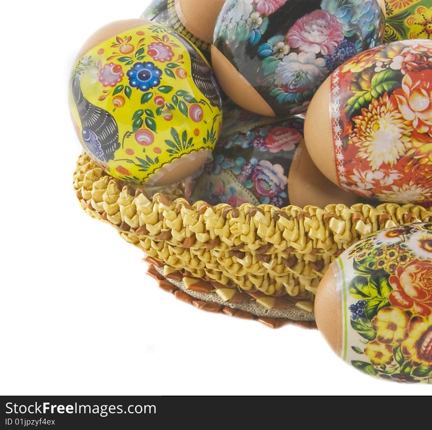 The easter decorated eggs lying in a wattled basket. macro shooting. Isolated over white