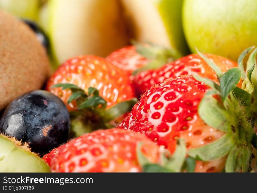 Assorted fresh fruits background including strawberry, apple, kiwi and black and green grape