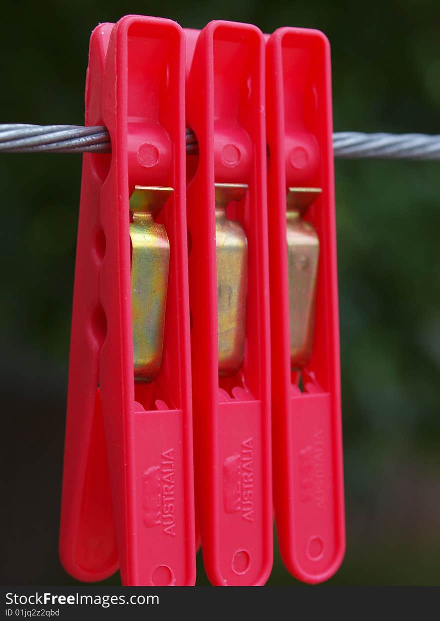 Three red pegs hanging on a clothes line. Three red pegs hanging on a clothes line