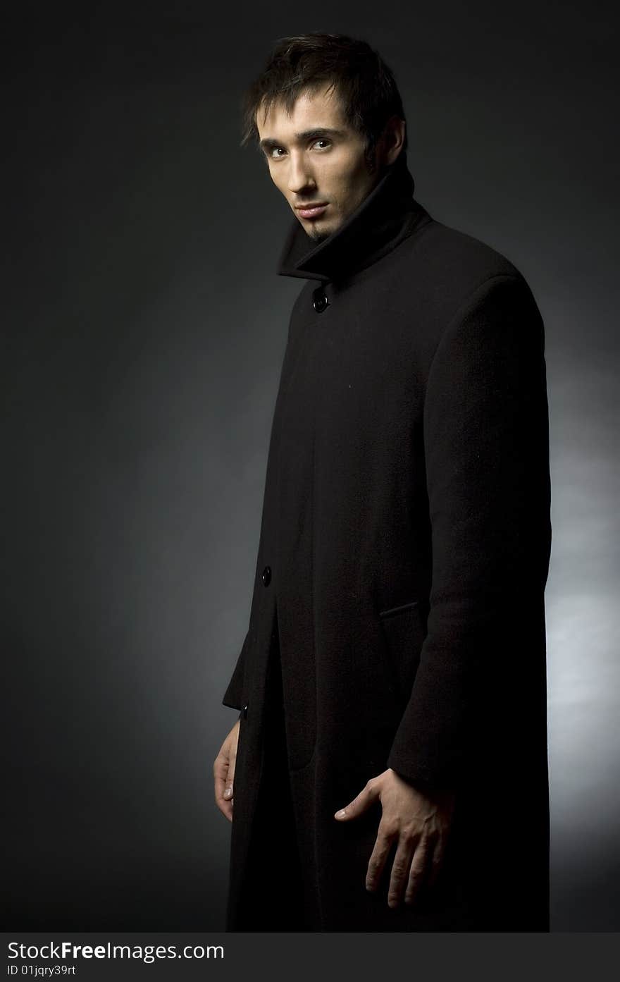 Portrait of a young business man with his hands on a dark background. Portrait of a young business man with his hands on a dark background