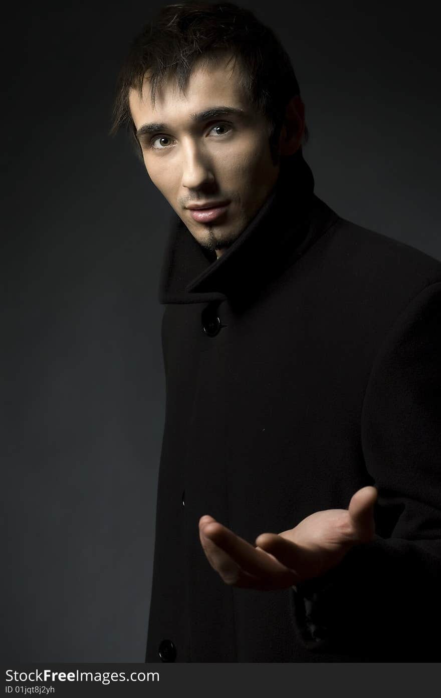 Portrait of a young business man with his hands on a dark background. Portrait of a young business man with his hands on a dark background