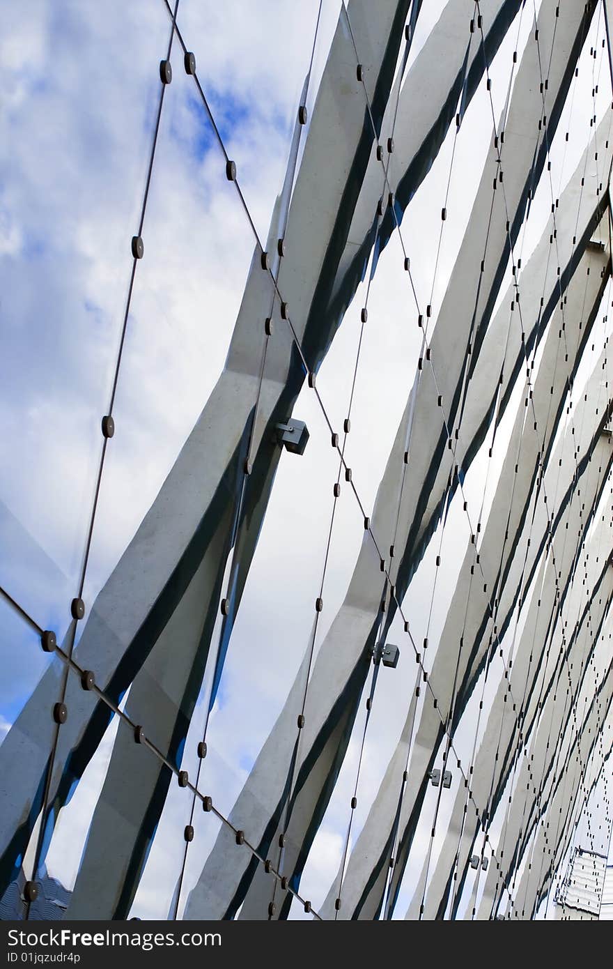 Urban composition with glass, steel, stone and blue sky with clouds that reflected on mirrored building's surface. Urban composition with glass, steel, stone and blue sky with clouds that reflected on mirrored building's surface.