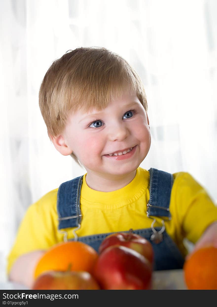 The child sits on a table with fruit. The child sits on a table with fruit