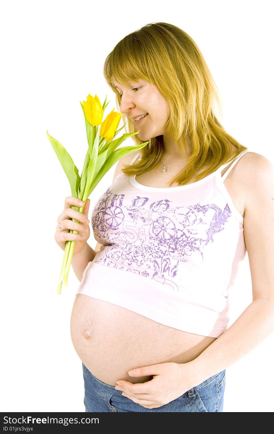 Young pregnant woman with yellow tulips on white