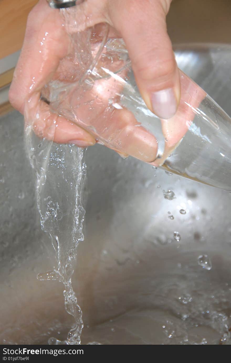 Hand washing wineglass in water in sink. Hand washing wineglass in water in sink