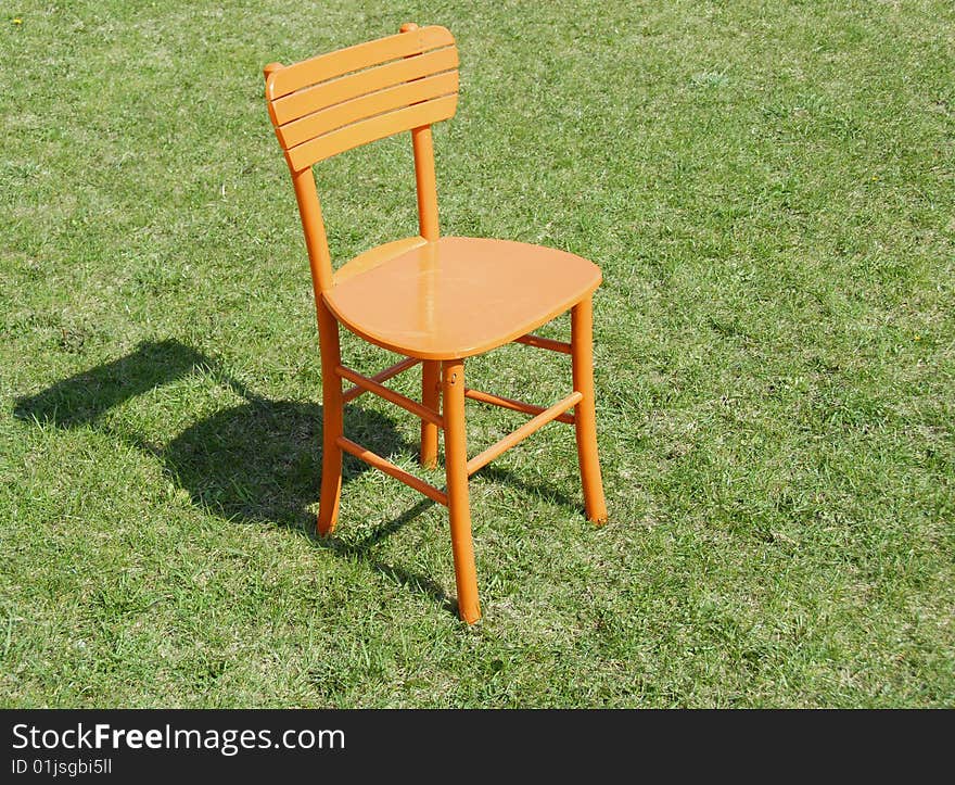 Orange wooden chair on green grass outdoor. Orange wooden chair on green grass outdoor