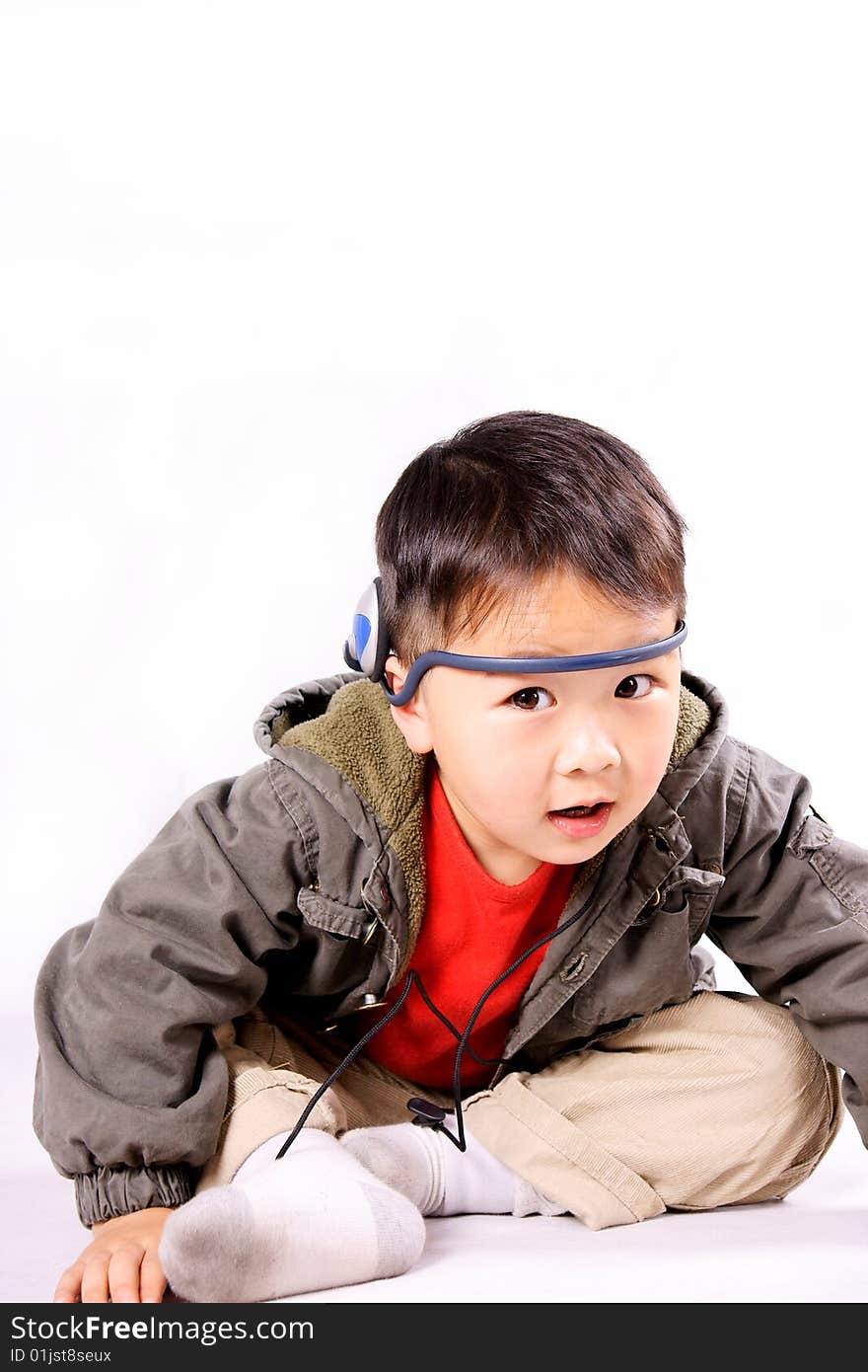 A picture of a little chinese boy listening to music with earphone, having great fun. A picture of a little chinese boy listening to music with earphone, having great fun