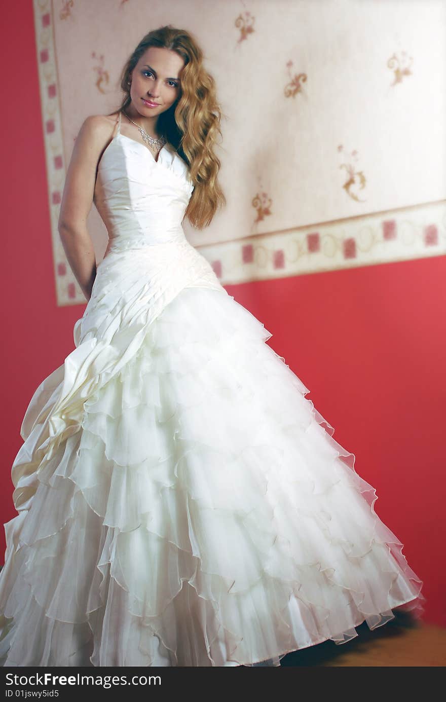 The bride in a white dress against a red wall. The bride in a white dress against a red wall