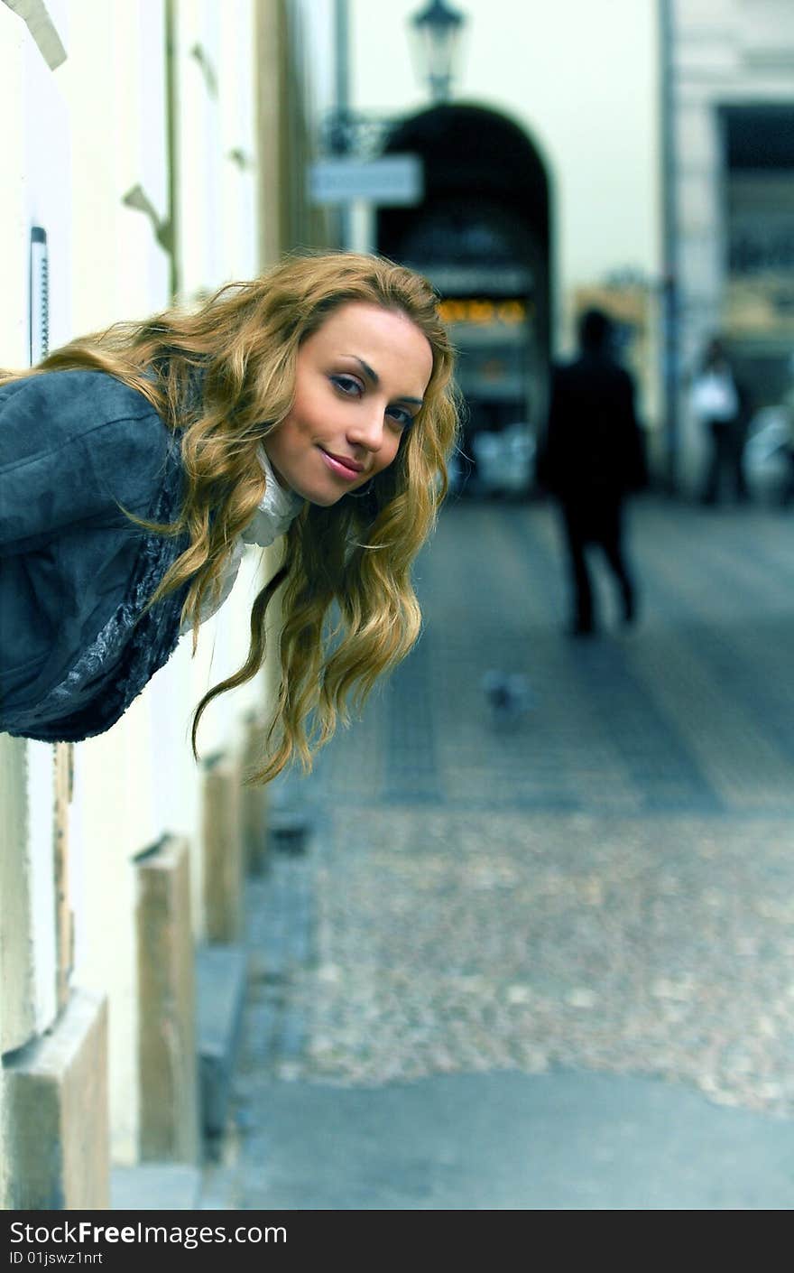 The woman in the street looks out of an arch and smiling