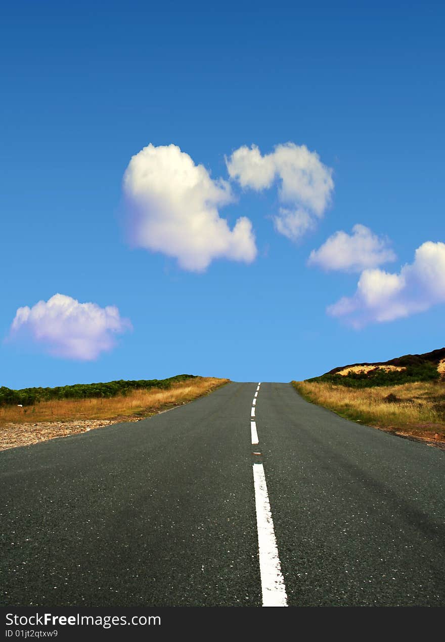 Country road leads towards blue cloudy sky