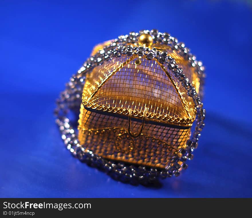 Close up of the box made of golden colored wire. Blue background. Close up of the box made of golden colored wire. Blue background.