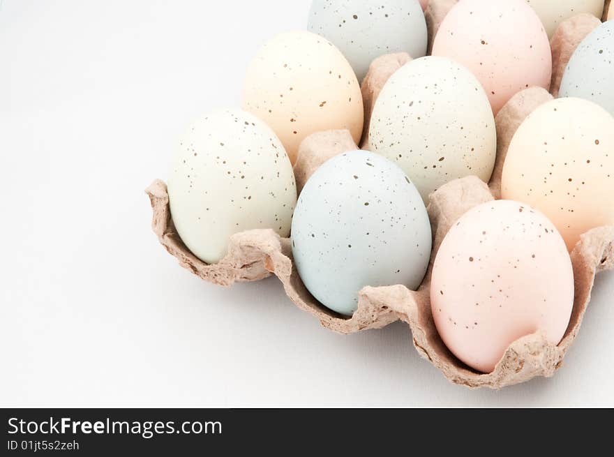 Pastel colored Easter eggs in crate on white background.