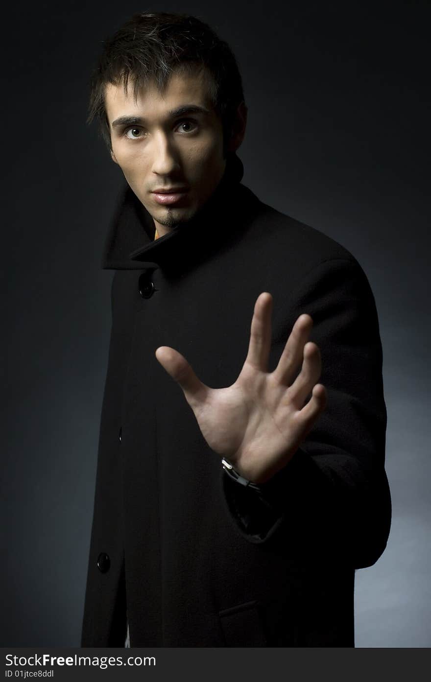 Portrait of a young business man with his hands on a dark background. Portrait of a young business man with his hands on a dark background