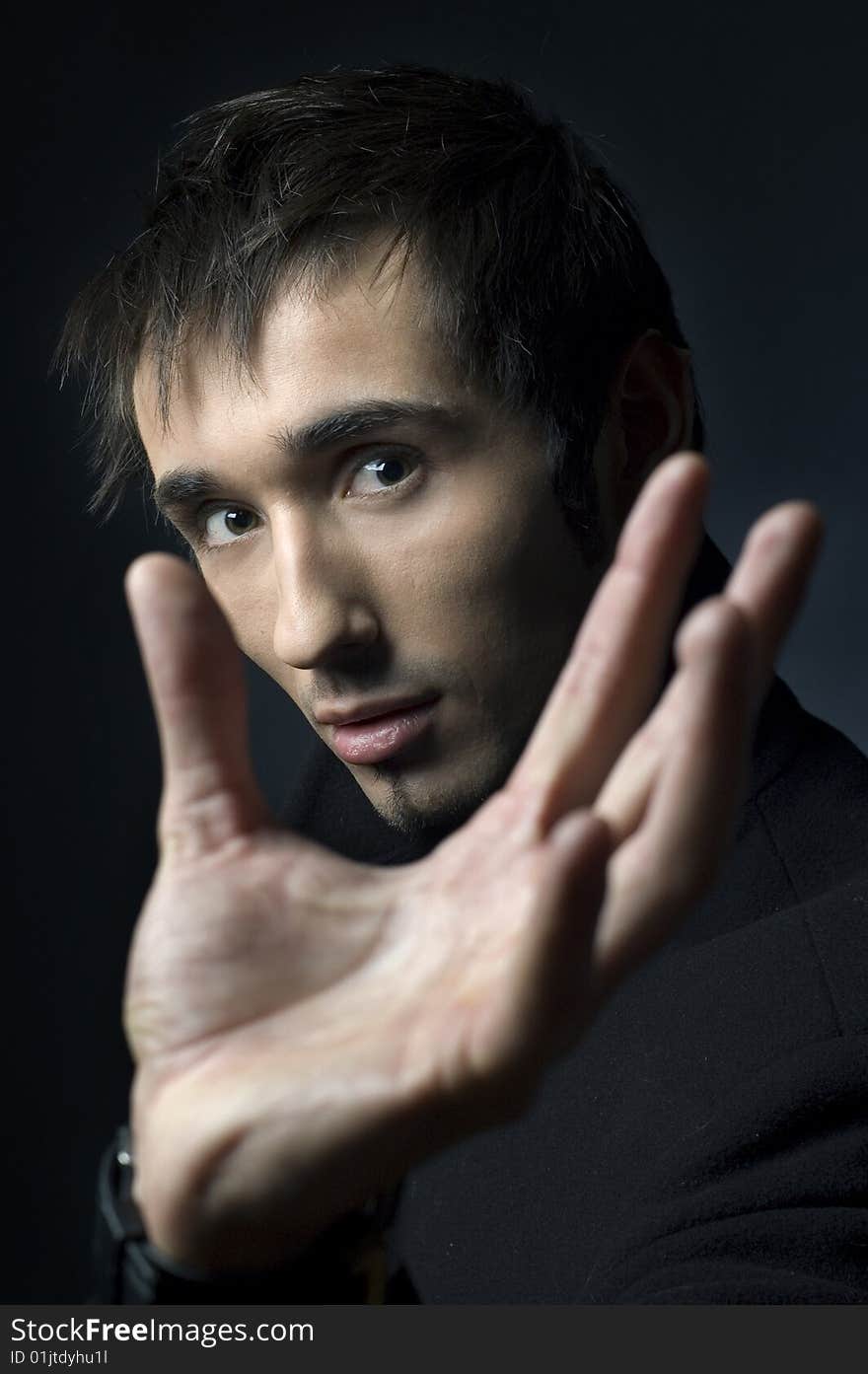 Portrait of a young business man with his hands on a dark background. Portrait of a young business man with his hands on a dark background