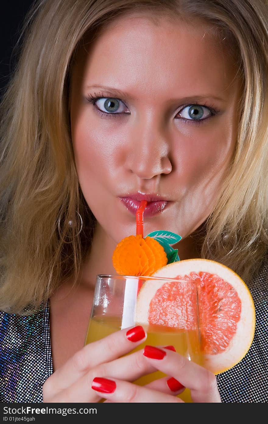 Beautiful girl in a silvery dress drinks a cocktail against a dark background. Beautiful girl in a silvery dress drinks a cocktail against a dark background