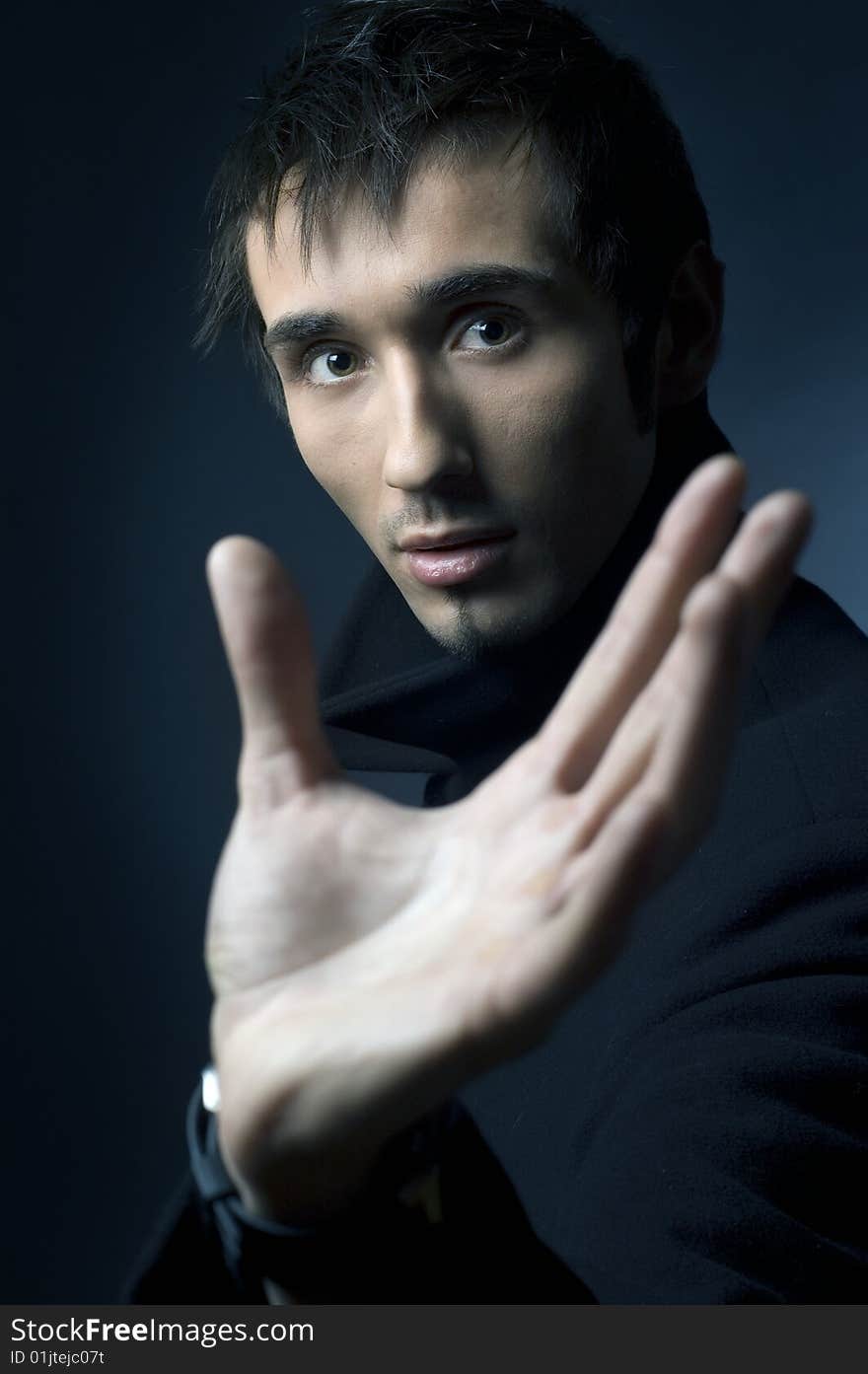 Portrait of a young business man with his hands on a dark background. Portrait of a young business man with his hands on a dark background