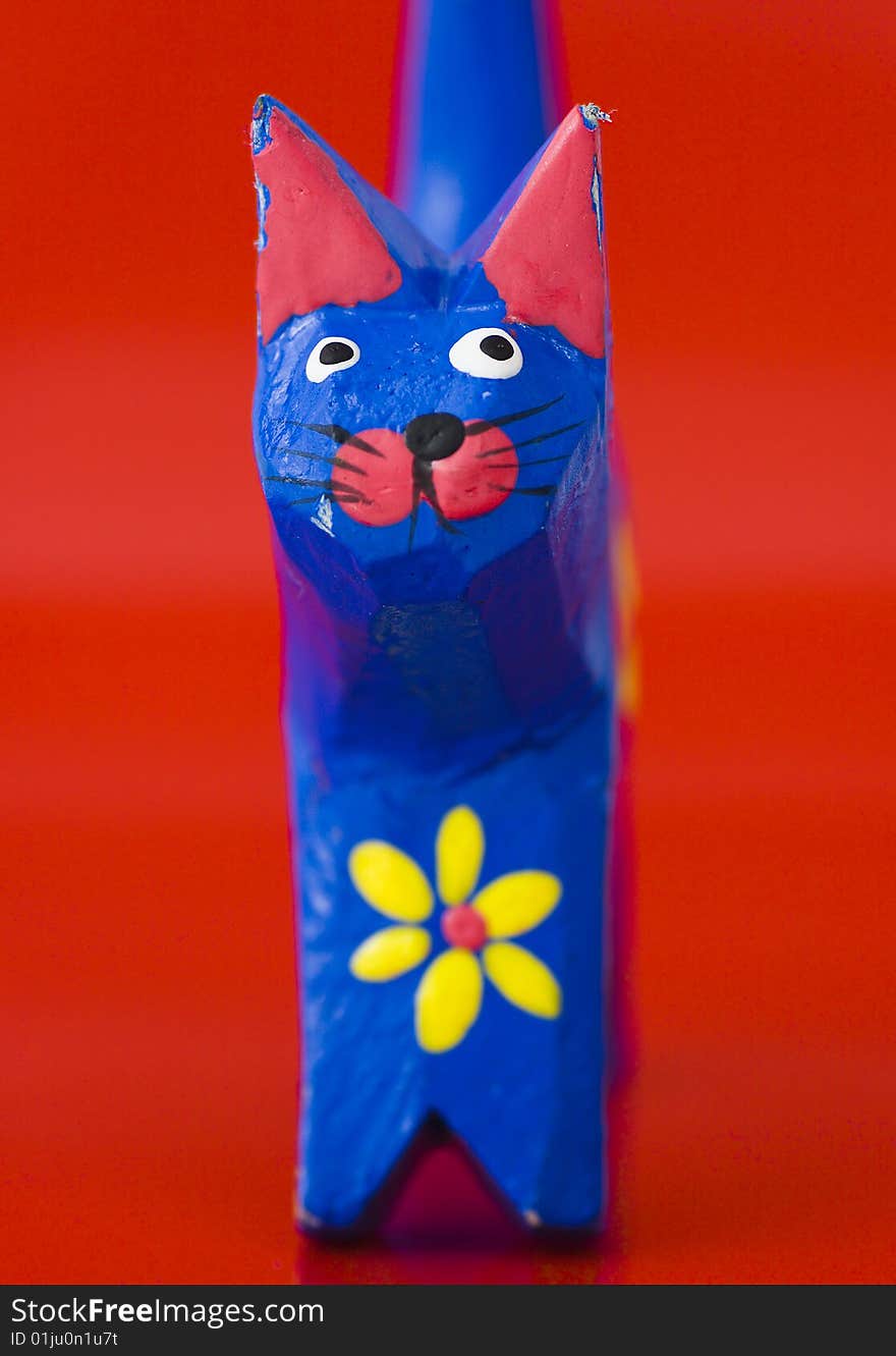 Sculpture of wooden painted cat on the red isolated background, from face-front view. Sculpture of wooden painted cat on the red isolated background, from face-front view