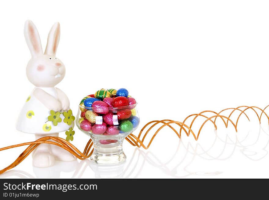 Colorful wrapped chocolate Easter eggs on white background, reflective surface