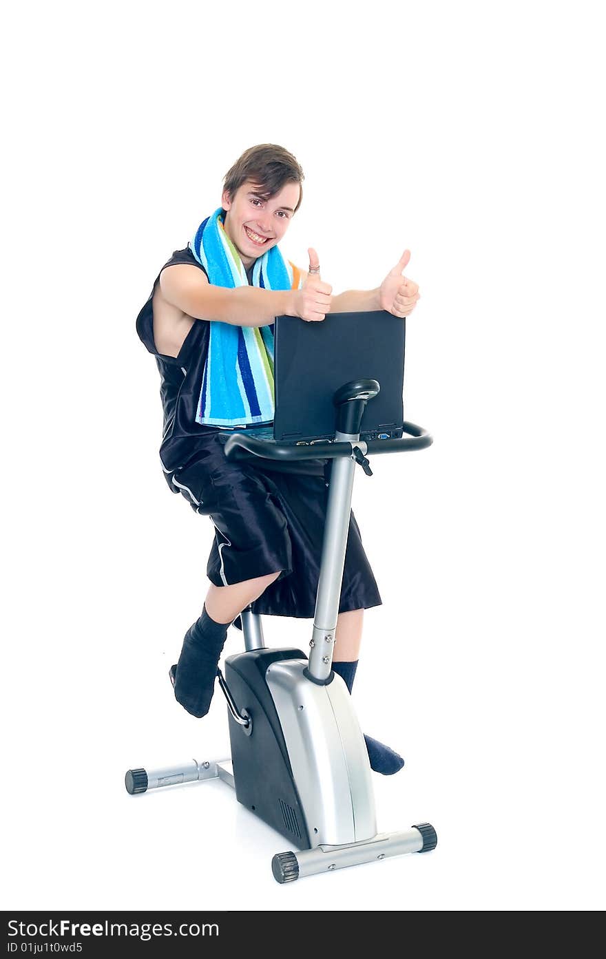 Young teenager boy doing fitness on hometrainer with laptop studying,. Young teenager boy doing fitness on hometrainer with laptop studying,