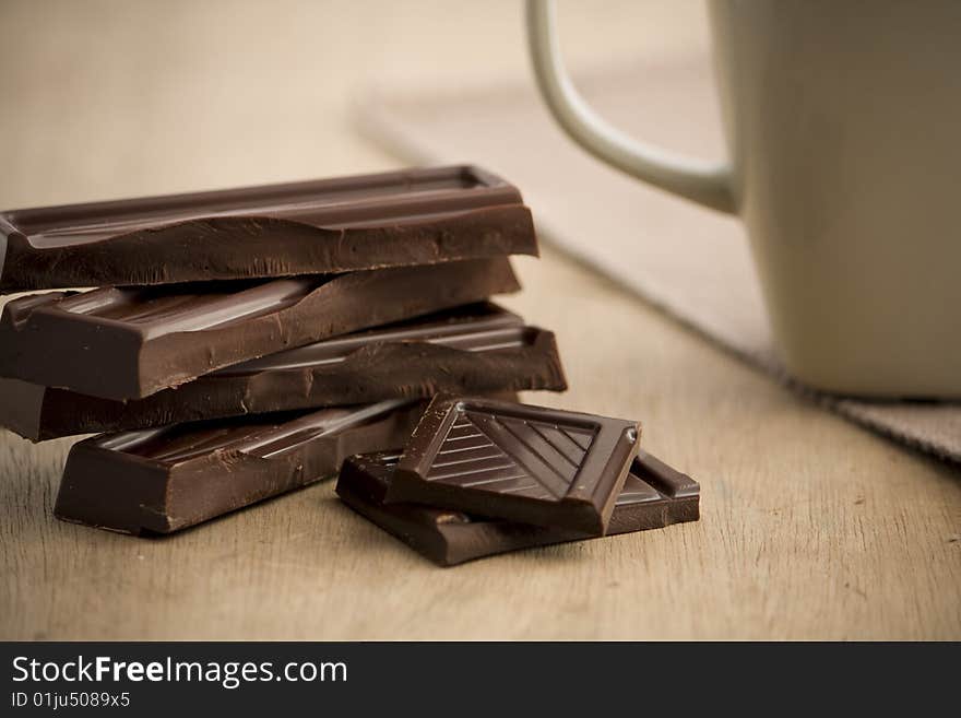 Chocolate with a mug of hot coco next to it. Chocolate with a mug of hot coco next to it