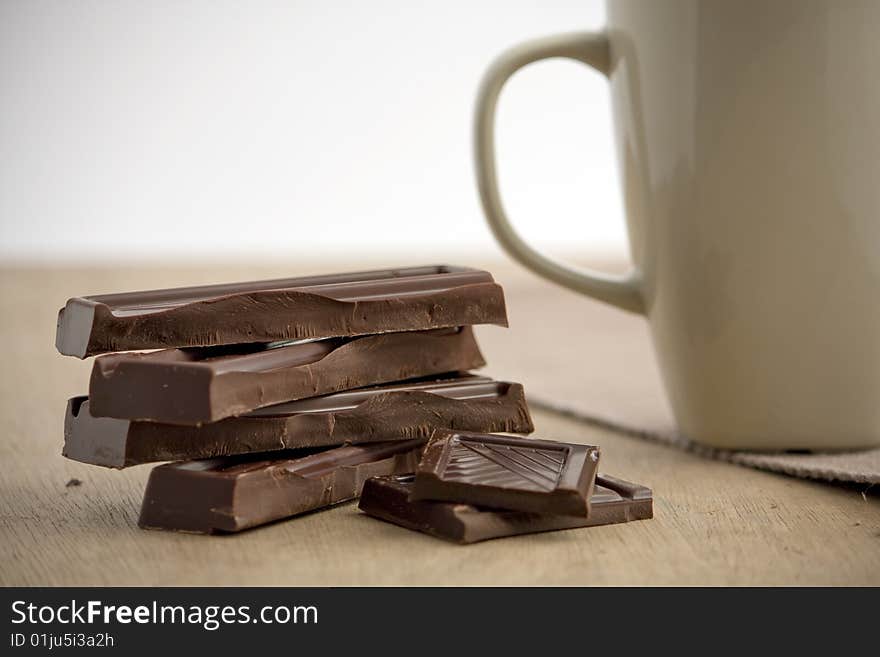 Chocolate with a mug of hot coco next to it. Chocolate with a mug of hot coco next to it