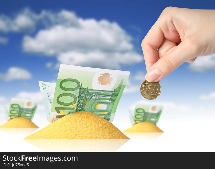 Financial concept. Hand, sand and money over blue sky background.