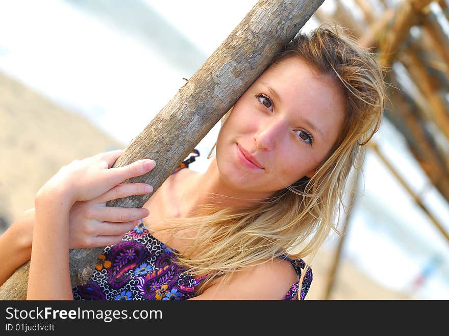 Beautiful smiling young blond girl on the beach holding a pole. Beautiful smiling young blond girl on the beach holding a pole