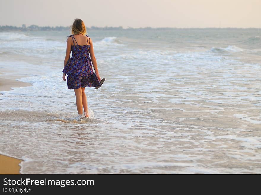 Beautiful young blond girl walking on beach