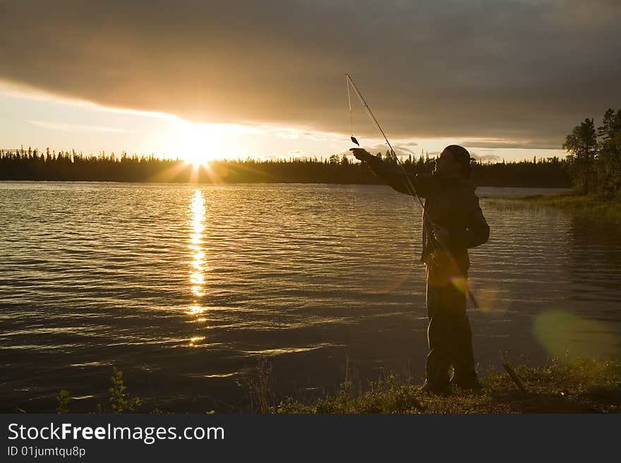 Fisherman on the shore with a small fish on a fishhook. Fisherman on the shore with a small fish on a fishhook