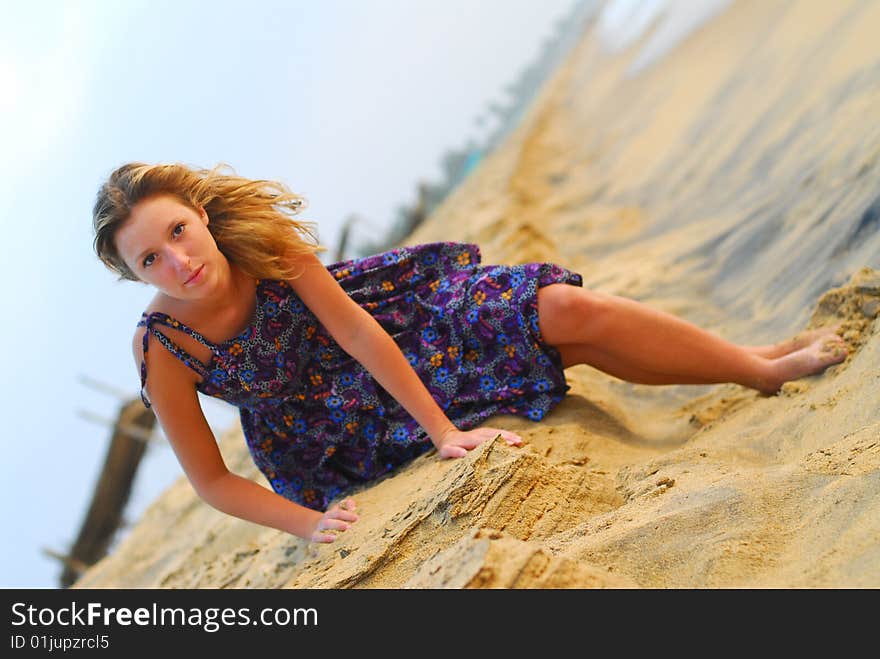 young blond girl sitting in dress on paradise beach leaning forward. young blond girl sitting in dress on paradise beach leaning forward