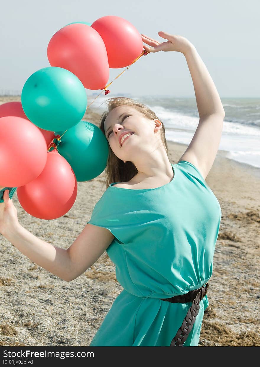 Emotional girl with balloons on the sea shore