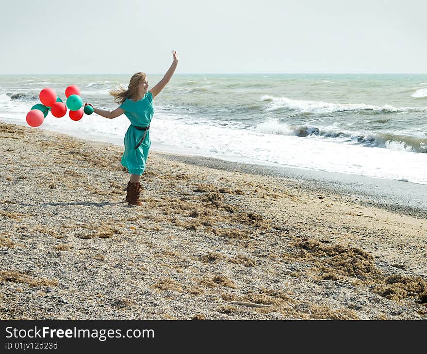 Emotional girl with balloons on the sea shore