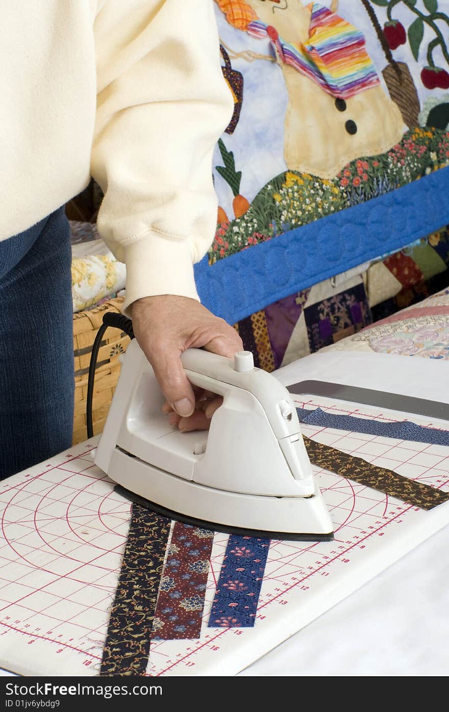 A quilter preparing fabric with iron prior to sewing. A quilter preparing fabric with iron prior to sewing.