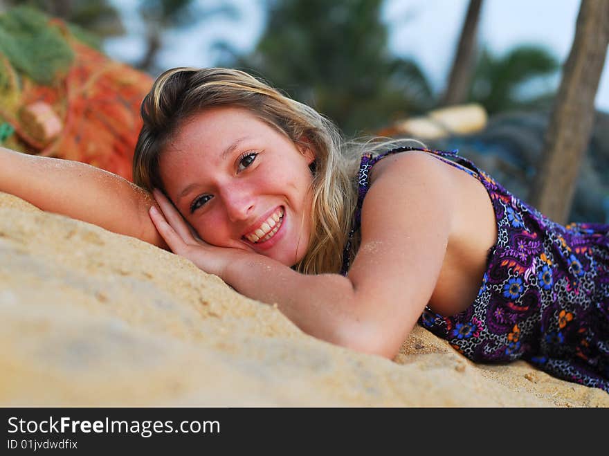 Young attractive smiling girl laying on the beach looking into the camera. Young attractive smiling girl laying on the beach looking into the camera