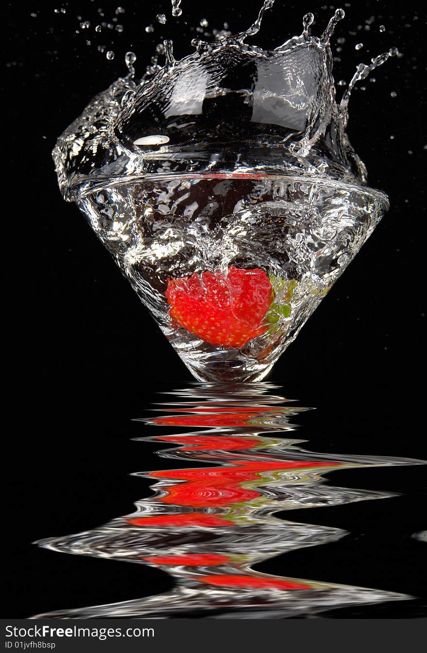 Falling strawberry in a glass with a drink