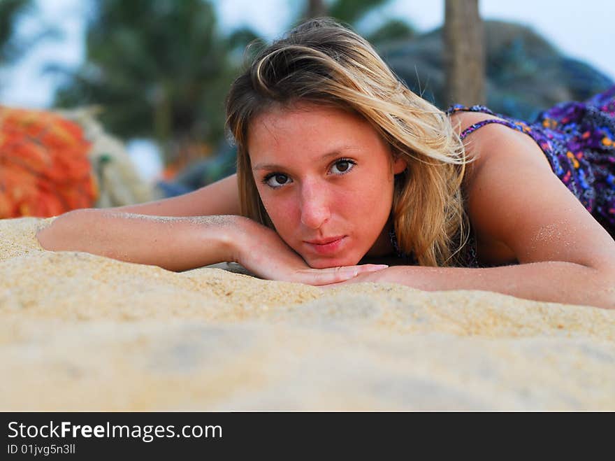 Young attractive girl laying on the beach looking into the camera. Young attractive girl laying on the beach looking into the camera