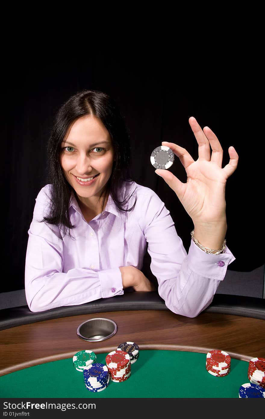 Pretty caucasian girl holds casino chip in hand over black