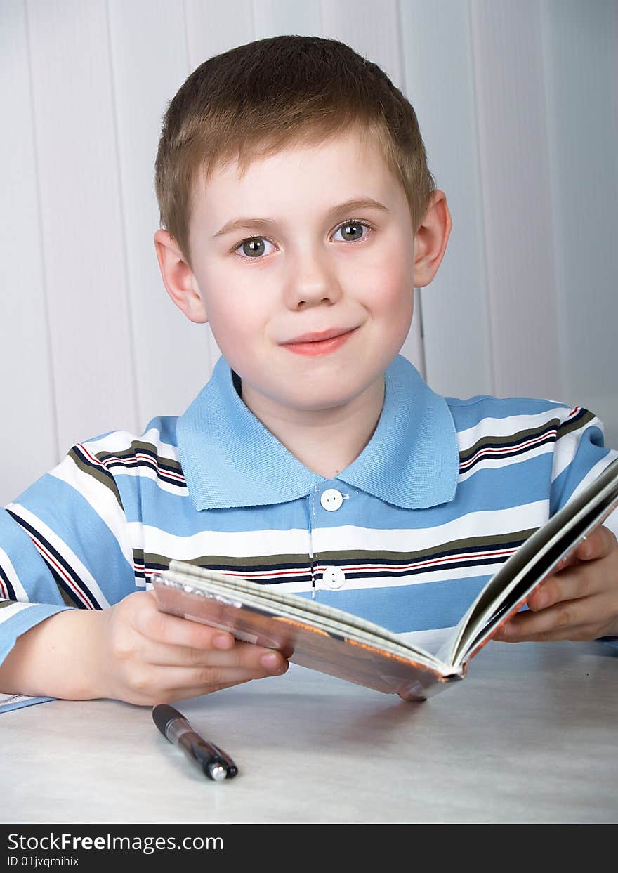 The litle boy doing homework on the table. The litle boy doing homework on the table