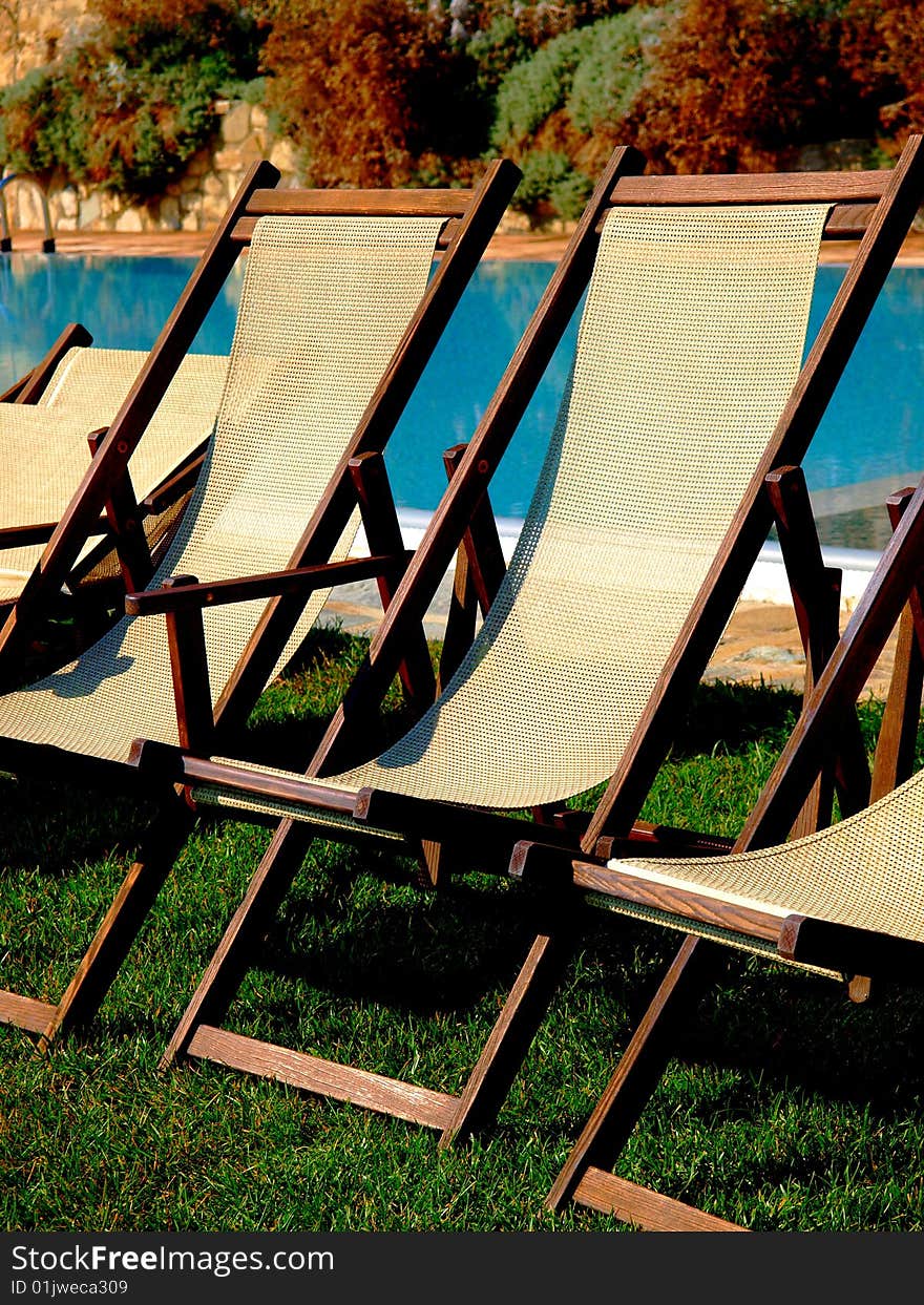 A good close up of some deck chairs behind a pool in a country house