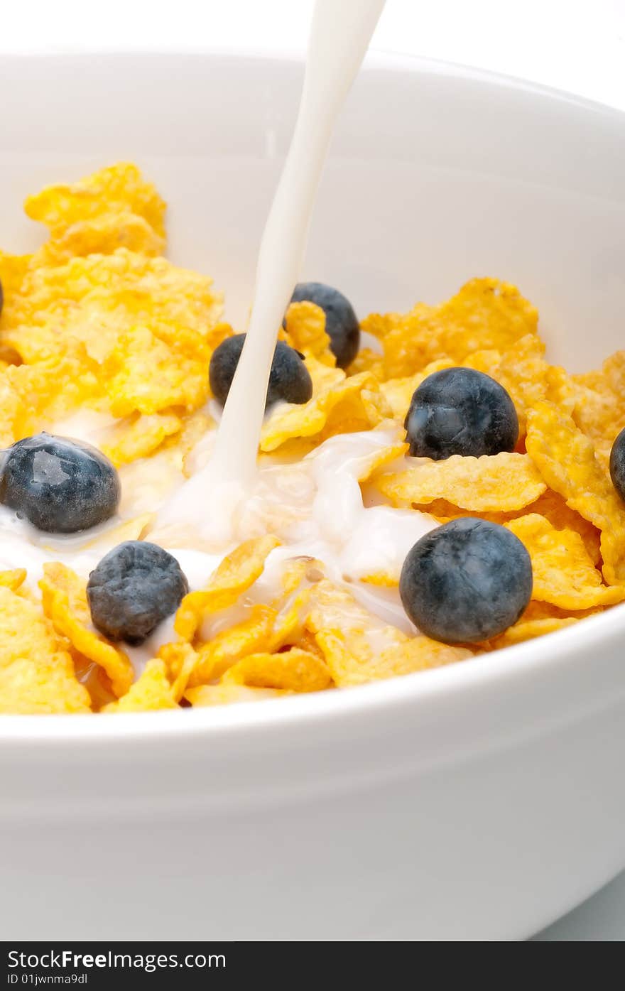 Pouring white milk into a bowl of breakfast flakes