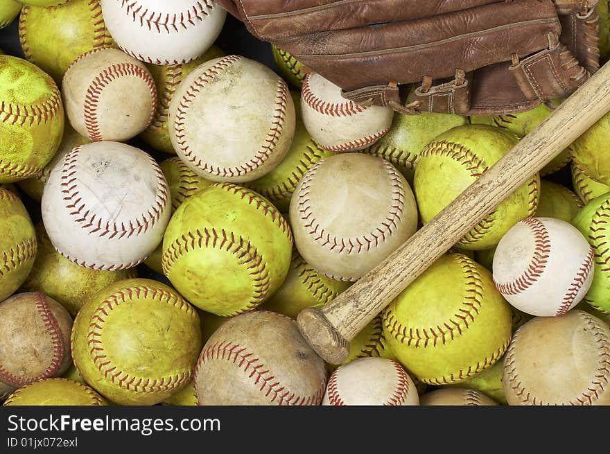 A picture of baseballs, softballs, a bat and glove. A picture of baseballs, softballs, a bat and glove